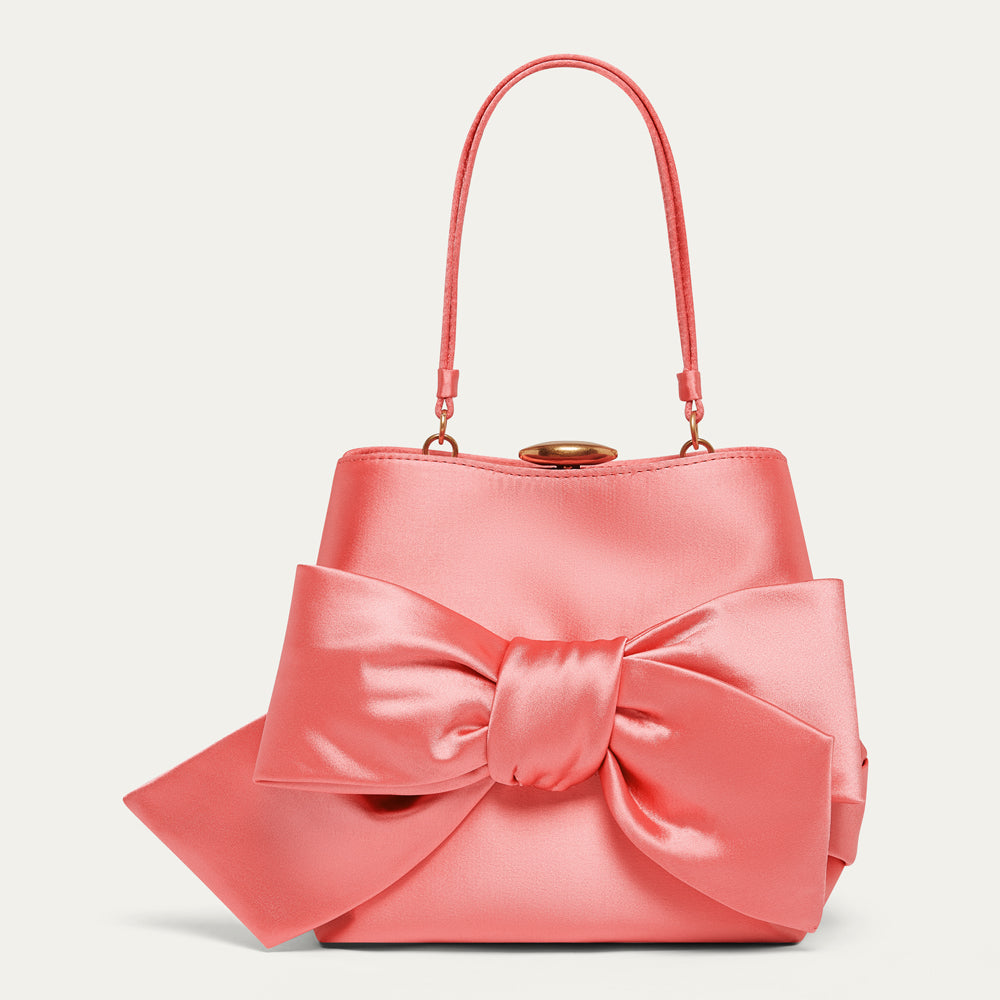Pink satin handbag with a large bow on a light gray background