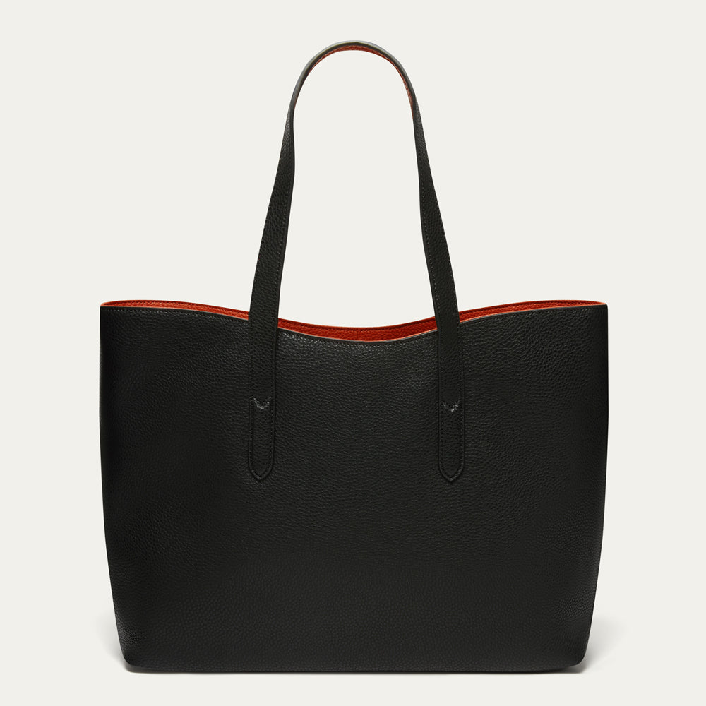 A black pebbled leather tote bag with dual shoulder straps and a contrasting red interior lining, shown against a plain off-white background.