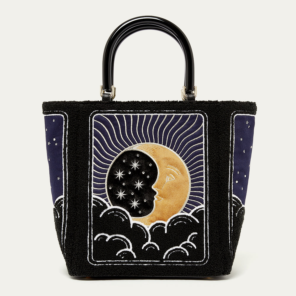 Black handbag with celestial design featuring a moon and stars on a white background