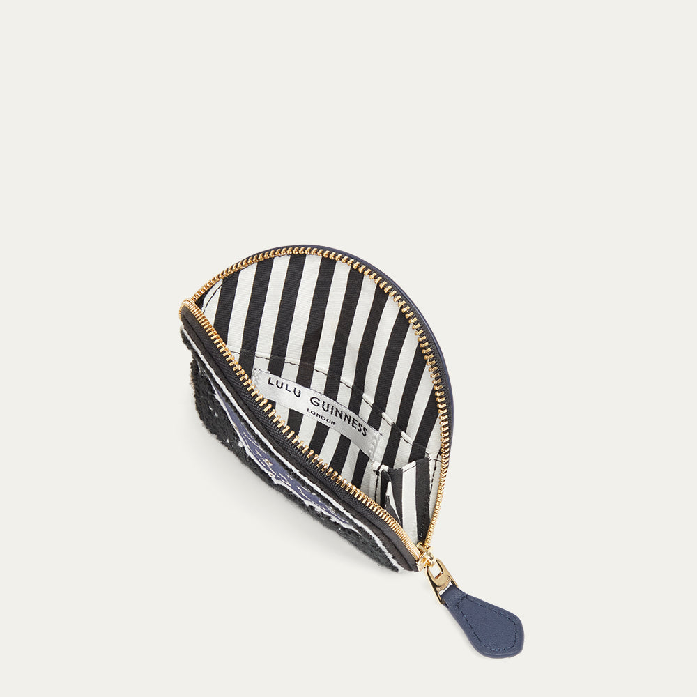 Navy leather coin purse with gold zipper open revealing a striped lining on a white background