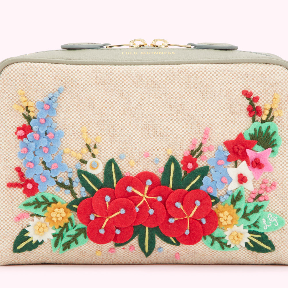 Close-up of a beige Lulu Guinness cosmetic bag with a grey leather trim and colourful felt flower embroidery.