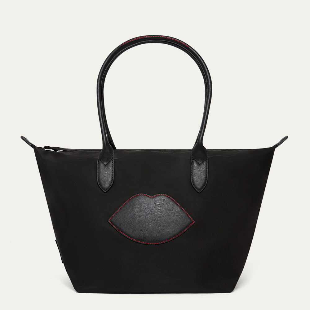 Black tote bag with a lip-shaped patch on a white background