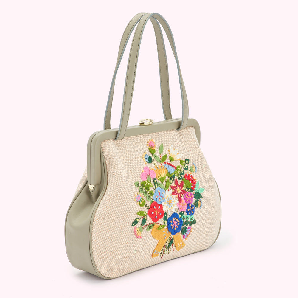 Sage green handbag with a beige canvas body embroidered with a colourful bouquet of flowers.