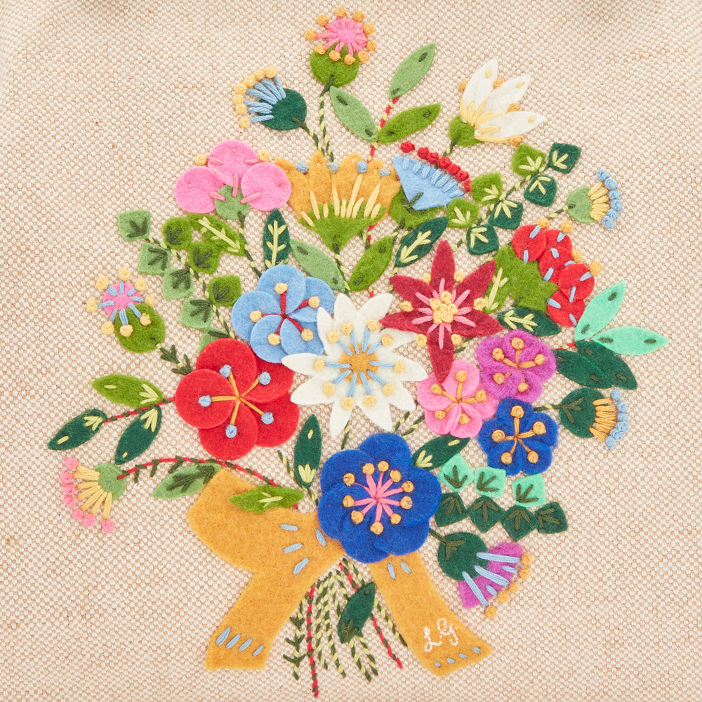 Embroidered bouquet of colourful felt flowers on a beige background.