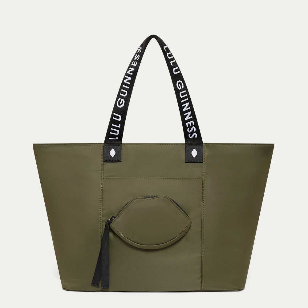 Green tote bag with Lulu Guinness straps and a lip shaped pocket on a light grey background