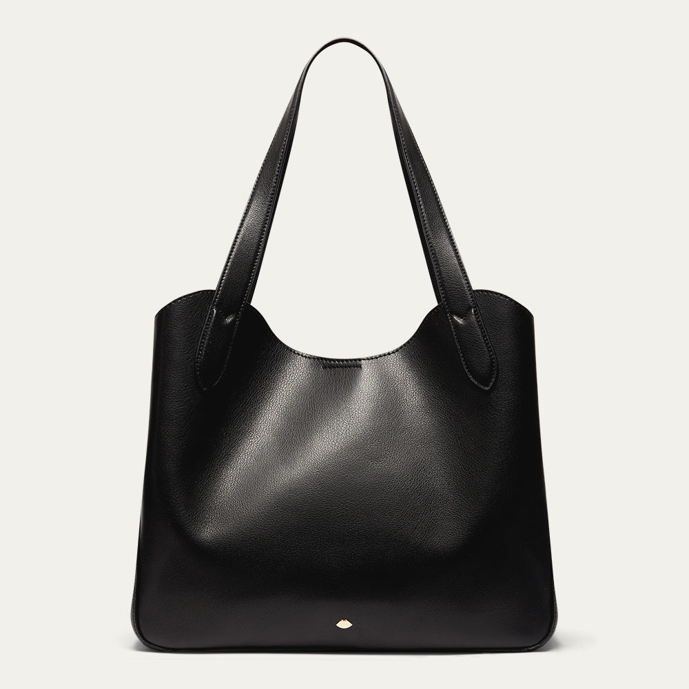 Black leather tote bag with gold lip accents on a light grey background