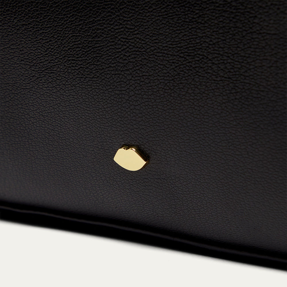 Close-up of a black leather product with a gold accent on a white background