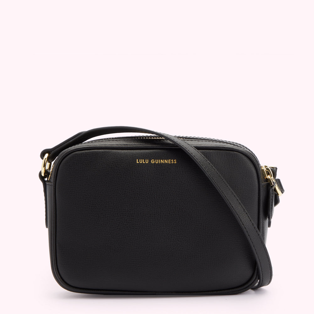 Image of back of black leather crossbody bag with strap folded across. Showing a gold foil print Lulu Guinness logo.