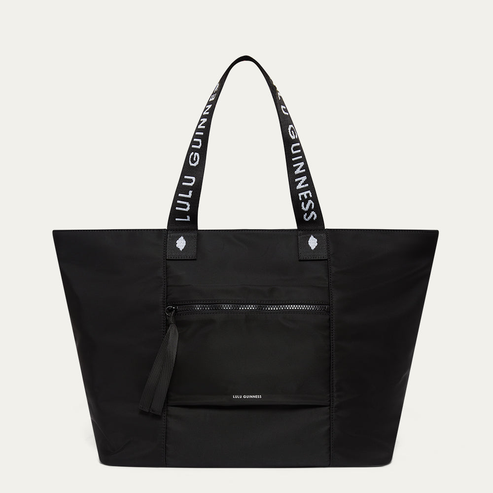 Black tote bag with 'Lulu Guinness' branding on a light grey background