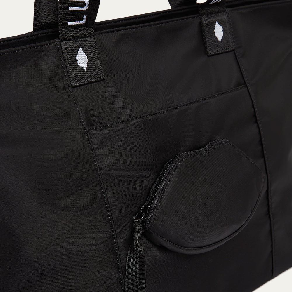 Black tote bag with a lip-shaped pocket and visible brand logo on a white background