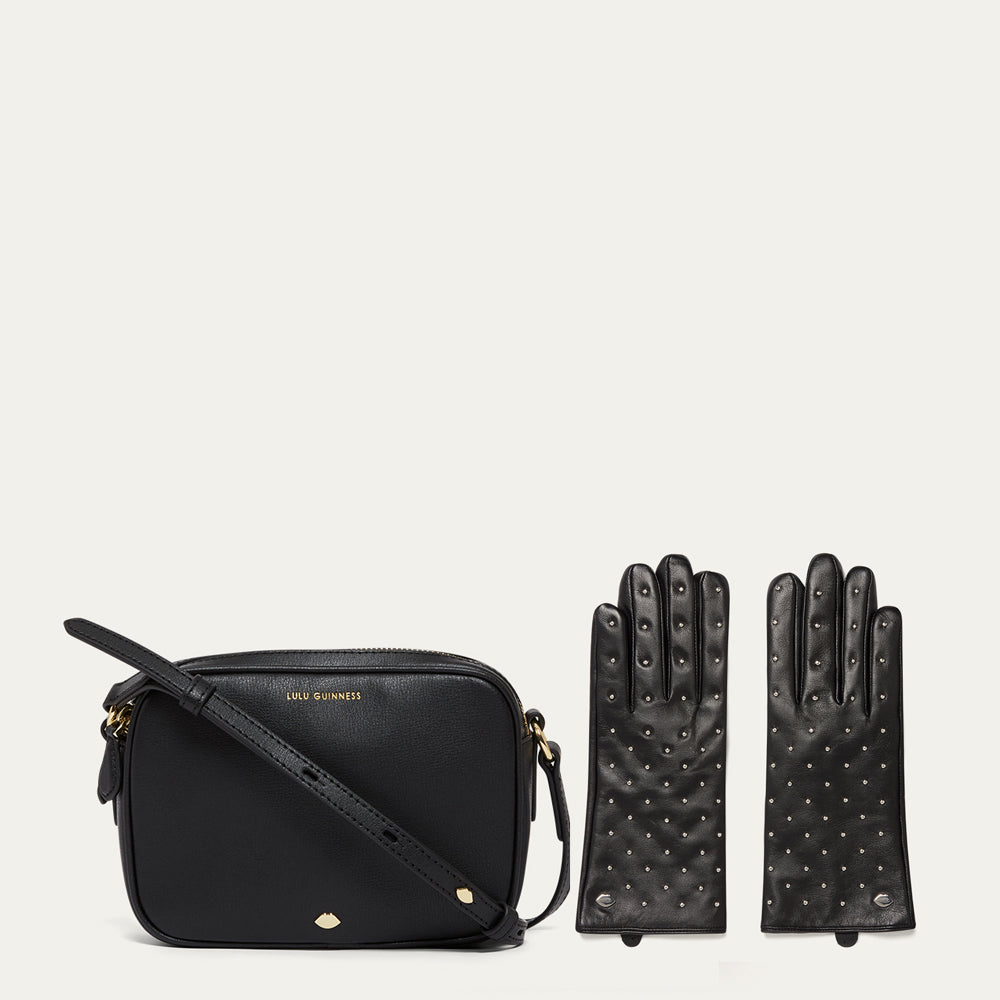 Black handbag and studded gloves on a light beige background
