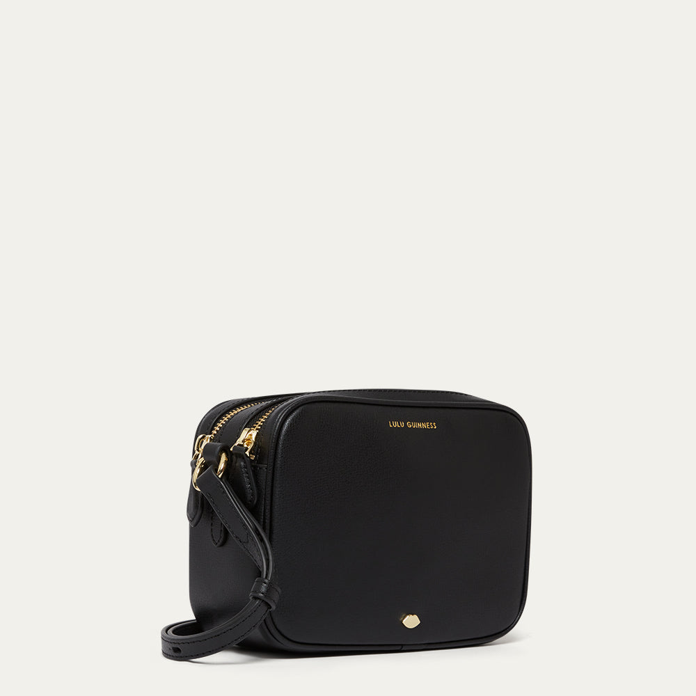 Black crossbody bag with gold accents on a light grey background