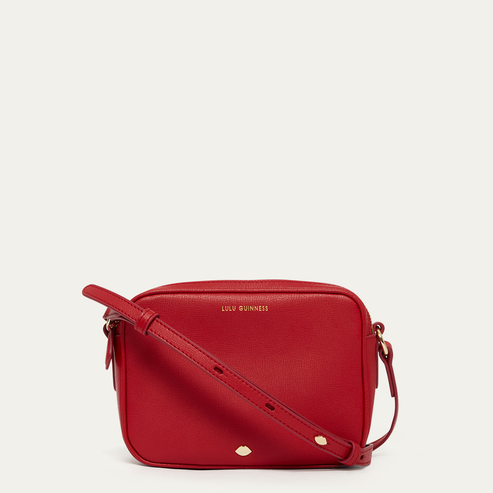 Red handbag with gold accents on a light beige background