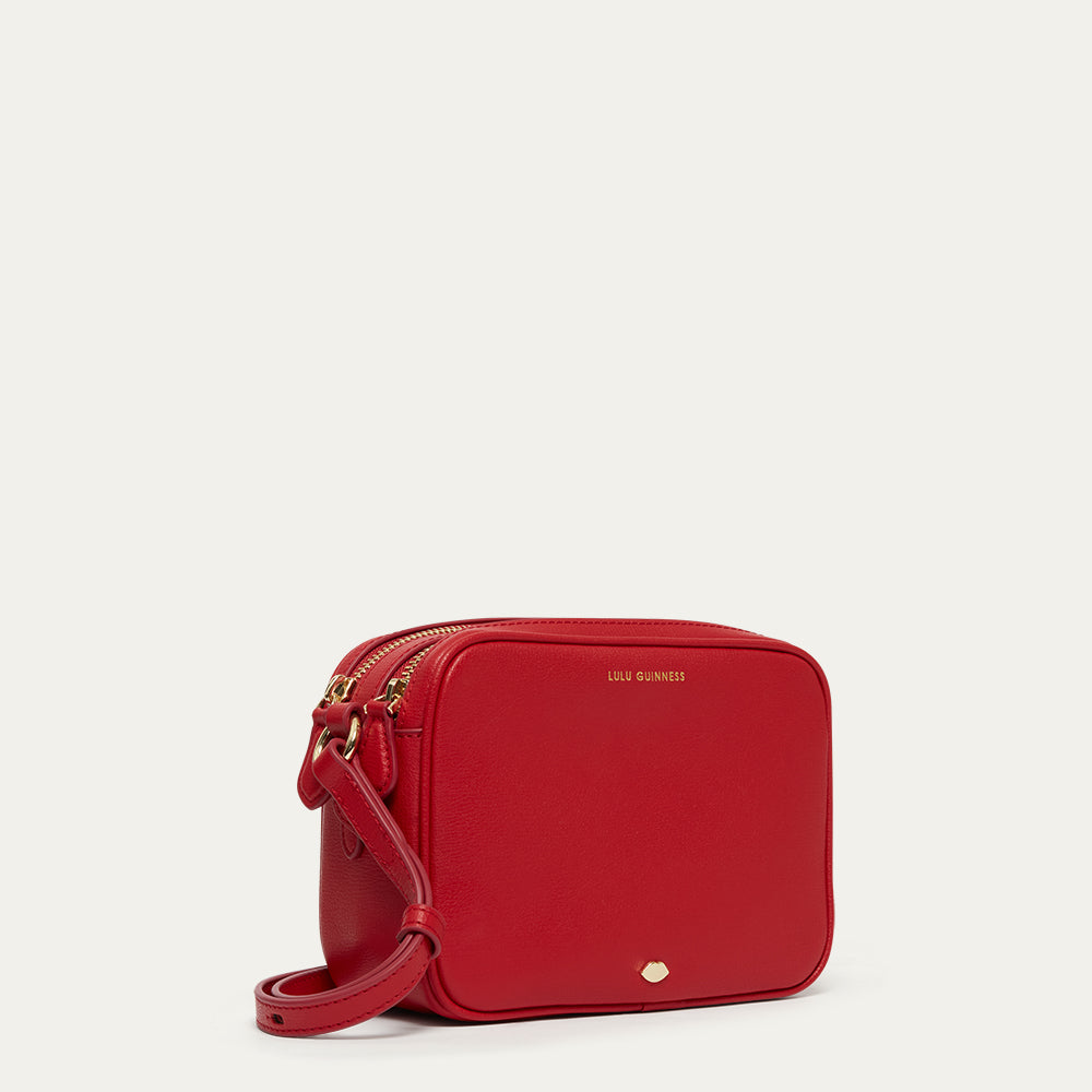 Red crossbody bag with gold accents on a light grey background
