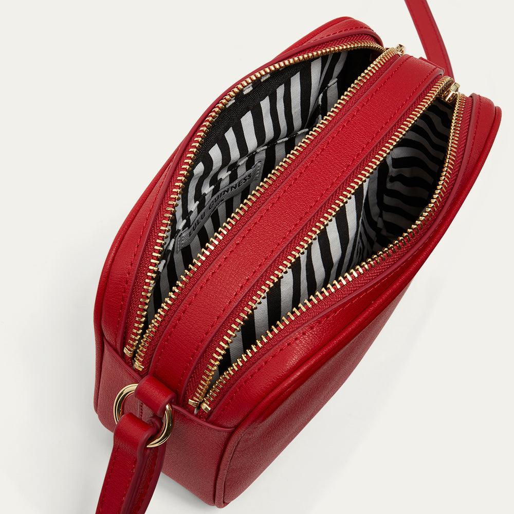 Red handbag with open with a black and white striped interior on a light grey background
