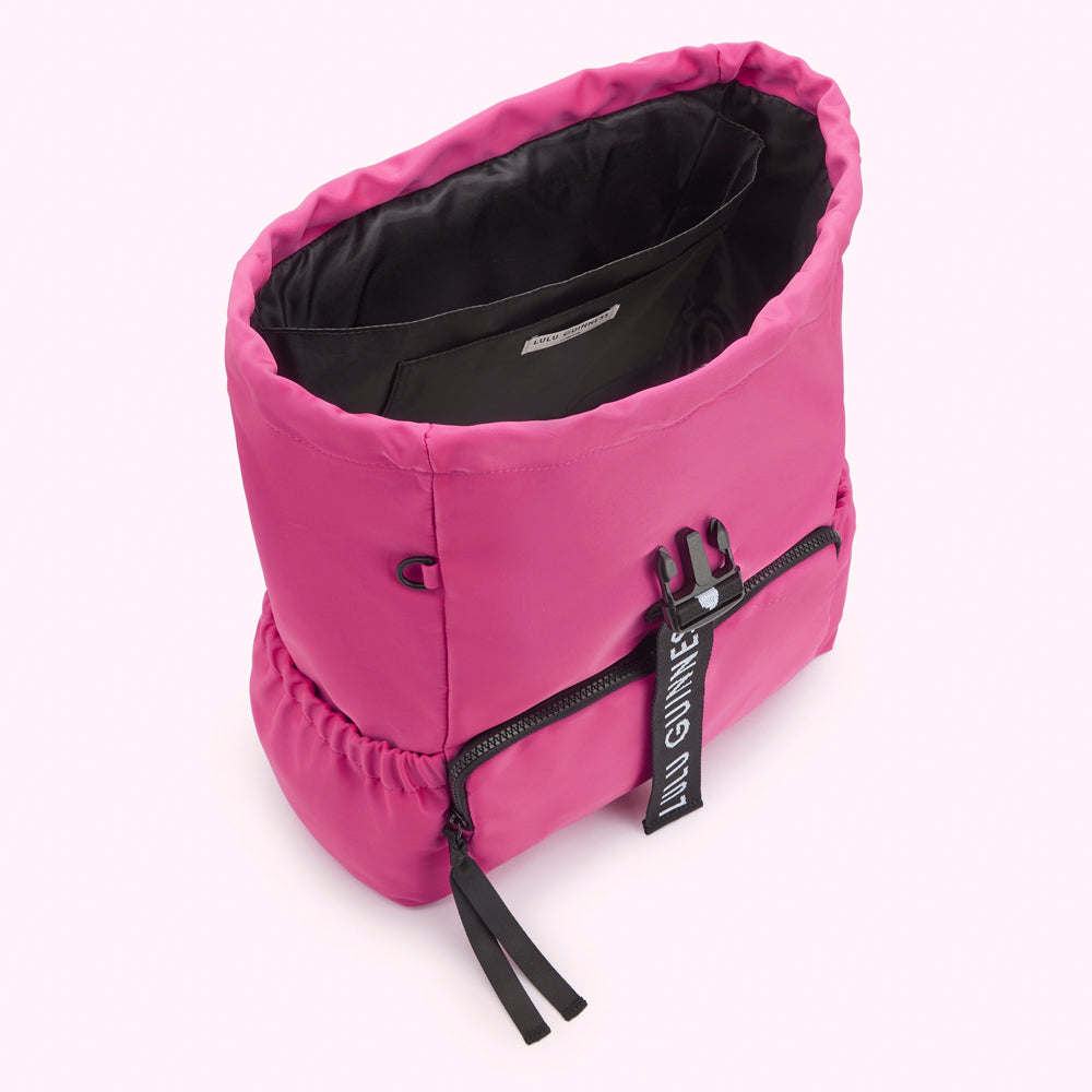 Bright pink Lulu Guinness backpack with black logo detail, viewed from above, showing the inside of the bag.