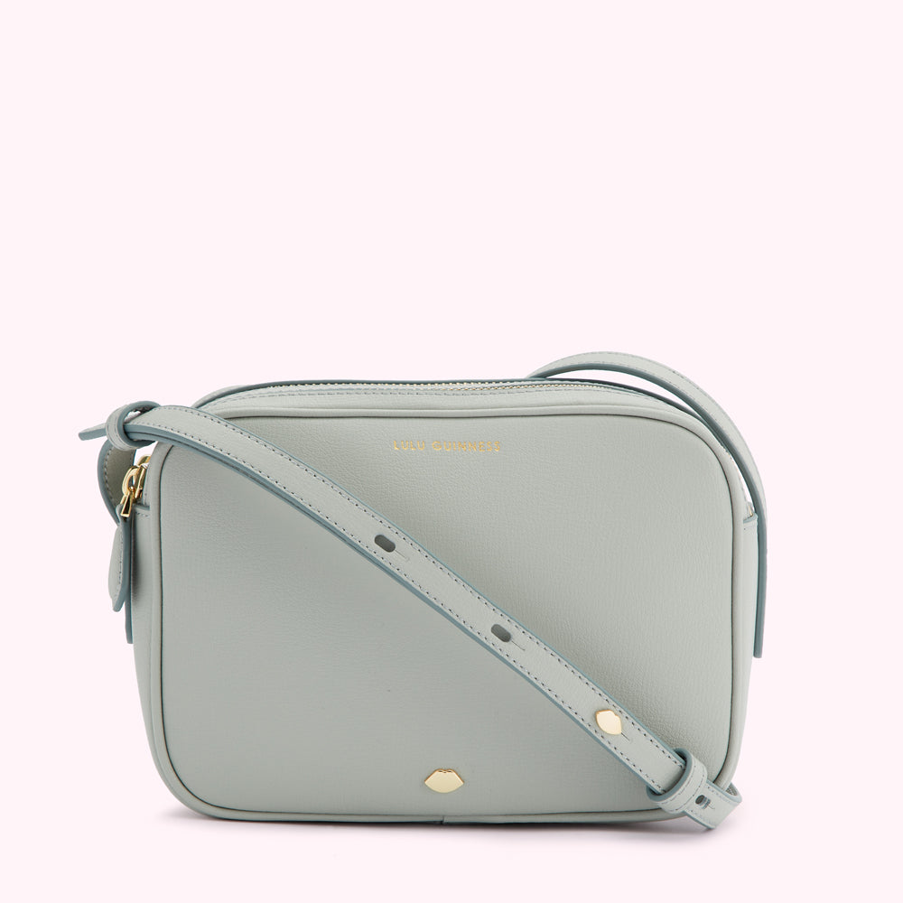 Light teal Lulu Guinness crossbody bag with gold zipper and logo.