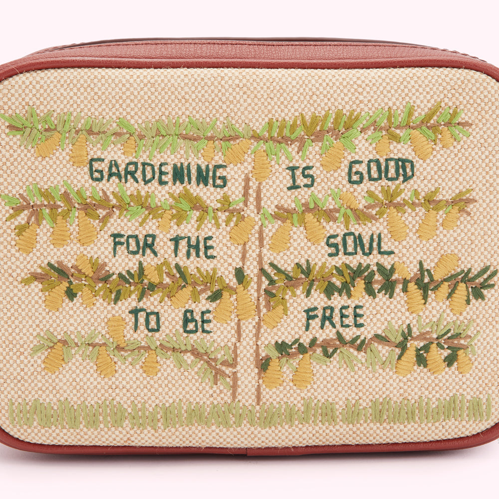 Beige crossbody bag with embroidered trees and the text "Gardening is good for the soul to be free".