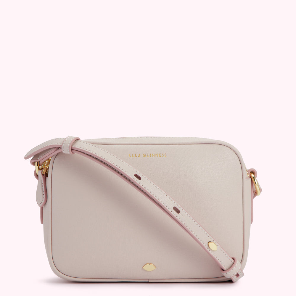 A light beige Lulu Guinness crossbody bag with a pink strap.