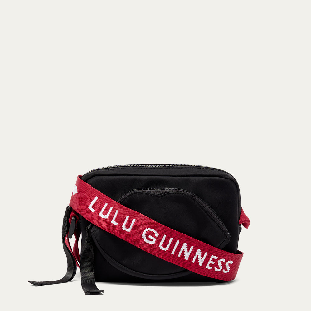 Black bag with a red strap featuring 'Lulu Guinness' on a light grey background