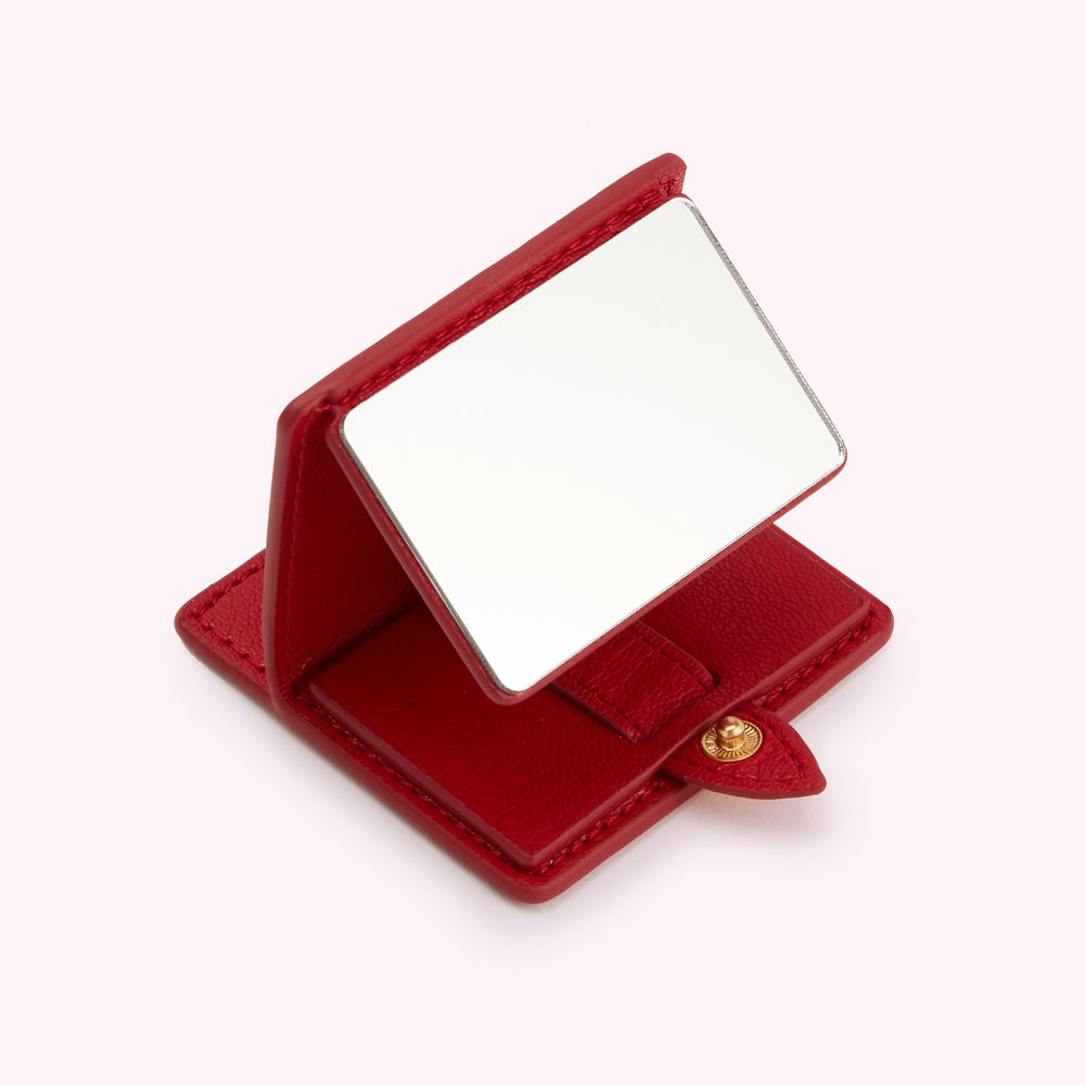 Red leather compact mirror open, showing reflective surface.

