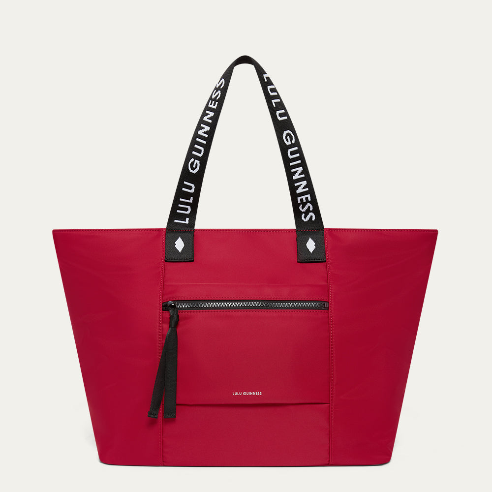 Red tote bag with black handles featuring 'Lulu Guinness' on a light grey background