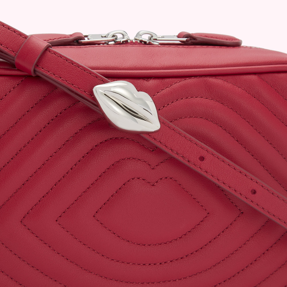 Close-up of a red quilted crossbody bag with a lip-shaped clasp.