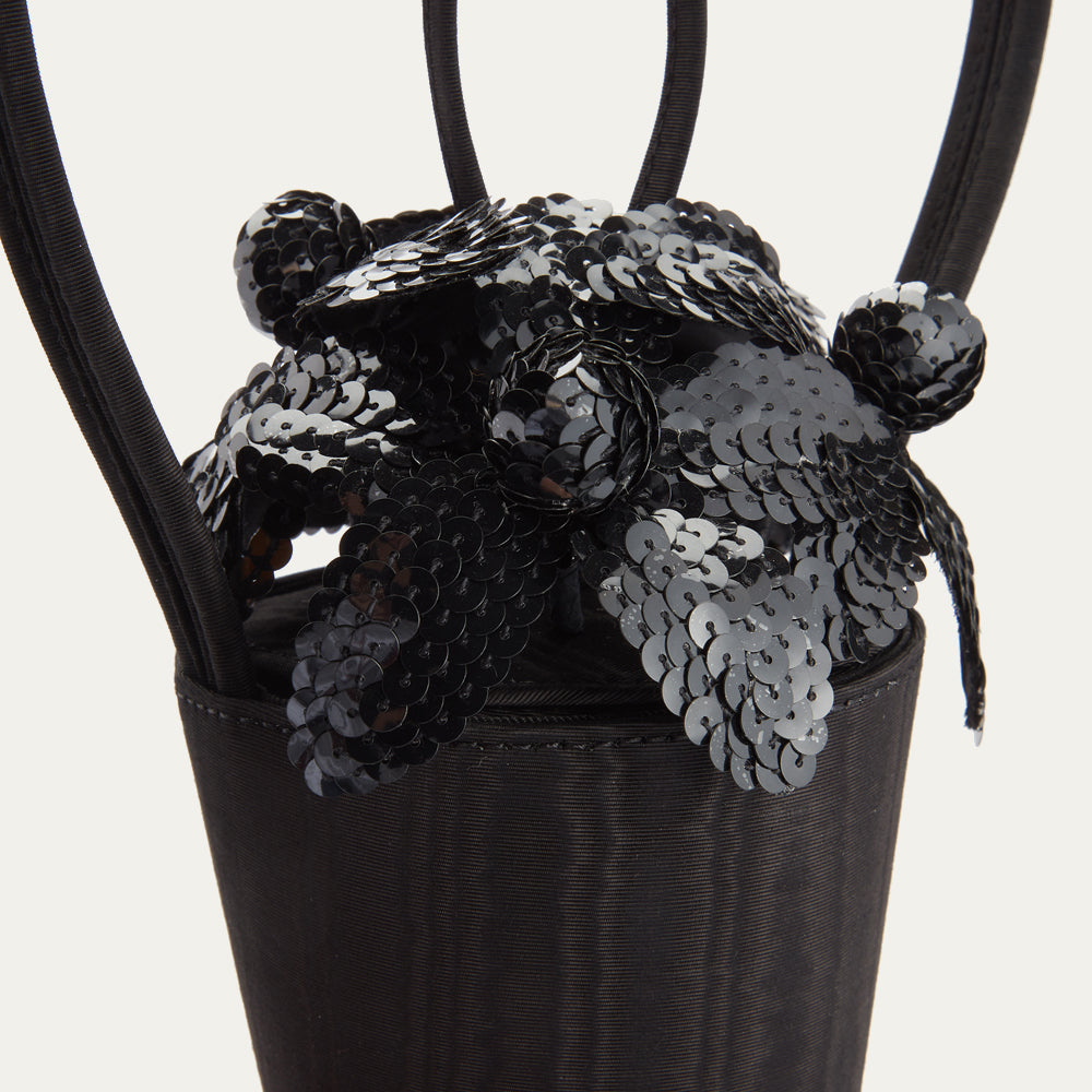 Detail close up image of sequin flowers on top of a black satin moire bag.