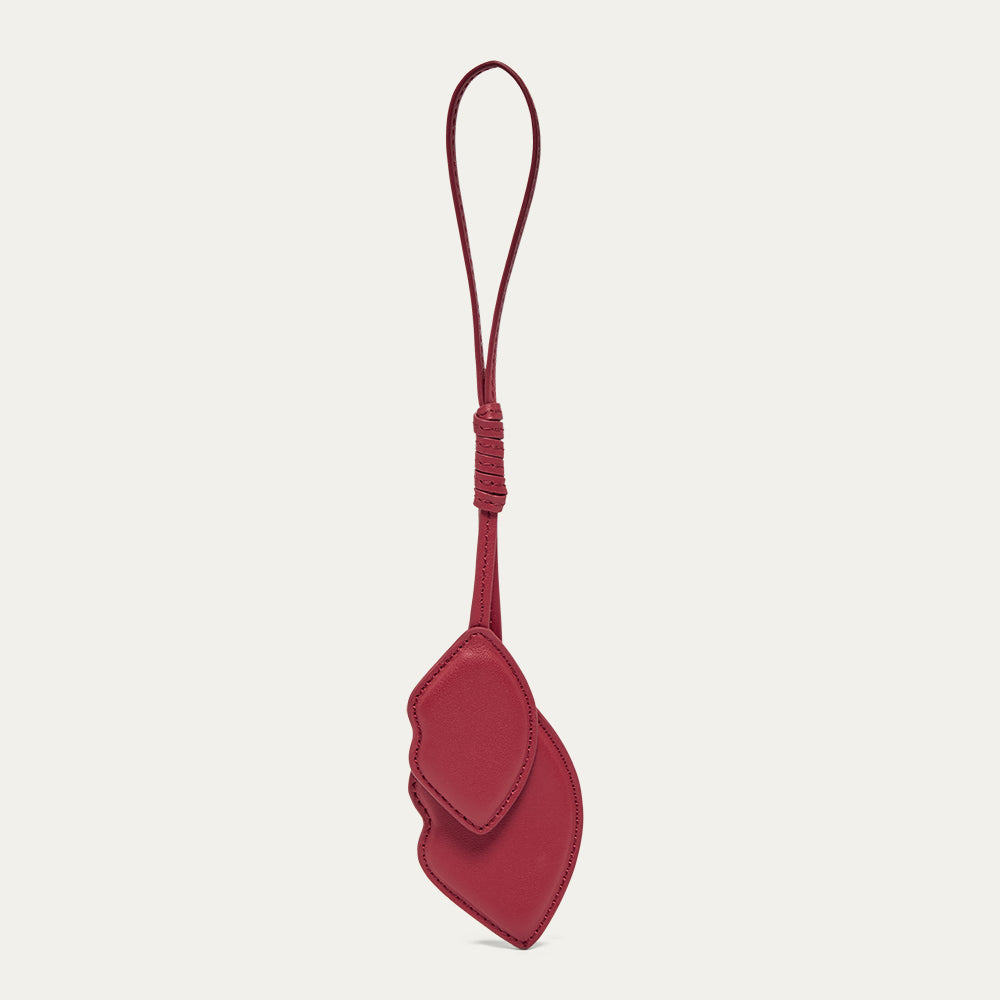 Lip shaped red leather charm on a light grey background