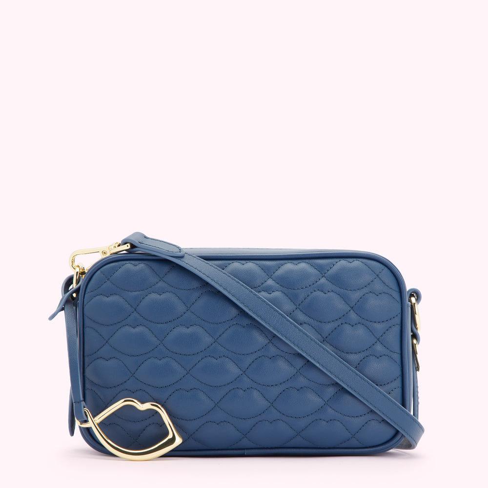 A quilted blue crossbody bag with a gold lip charm.