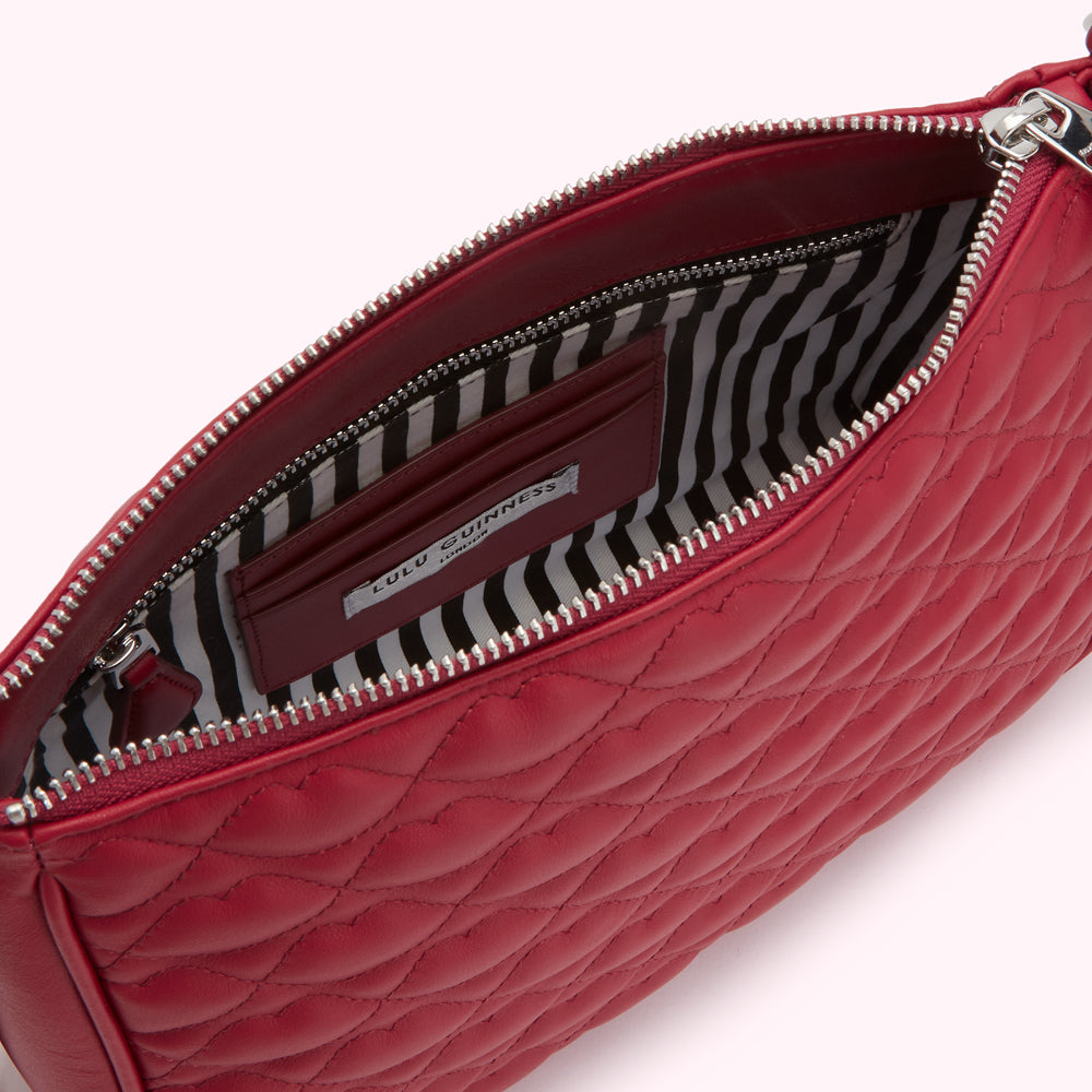 Red quilted leather Lulu Guinness purse open to show black and white striped interior lining and brand label.