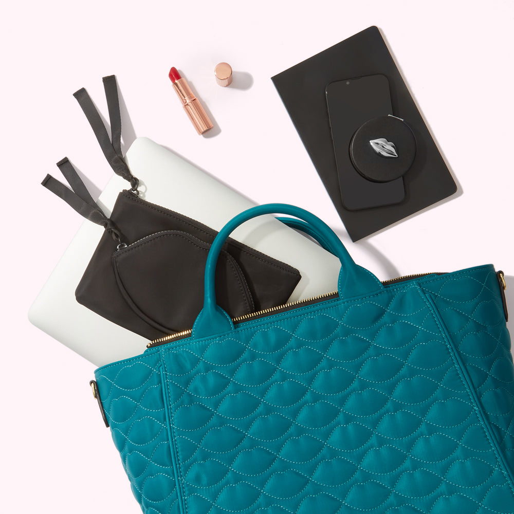 Teal quilted tote bag with laptop, phone, makeup, and accessories inside.
