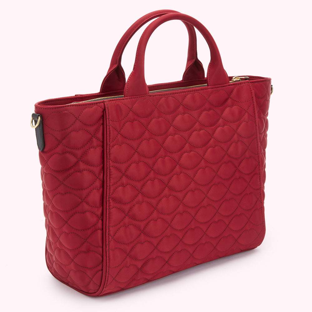 Red quilted tote bag with lip-shaped pattern.

