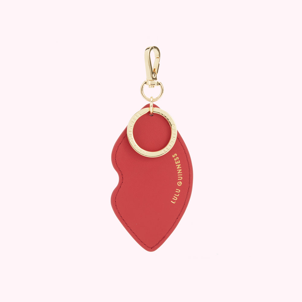 Back image of a red leather lip shaped keyring with gold foil print 'Lulu Guinness' logo and branded clip.