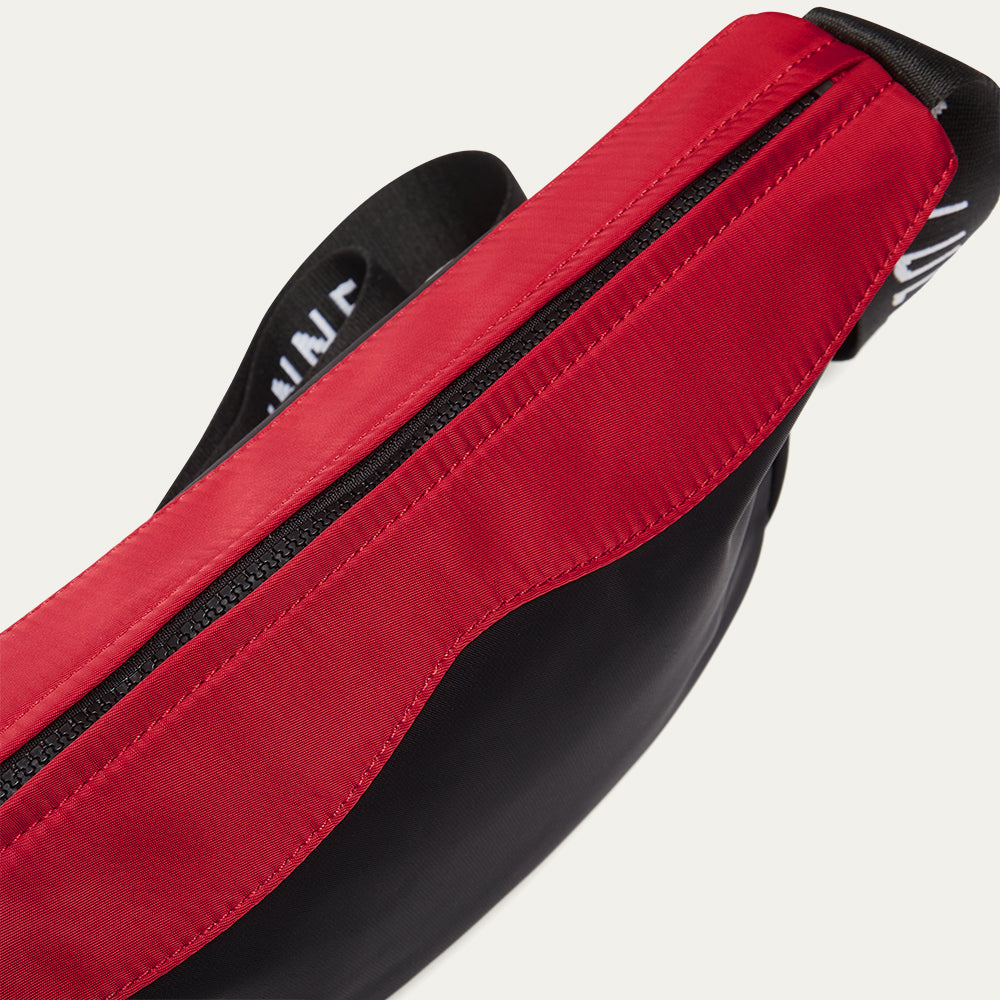 Close-up of a red and black bag with visible branding on a light gray background