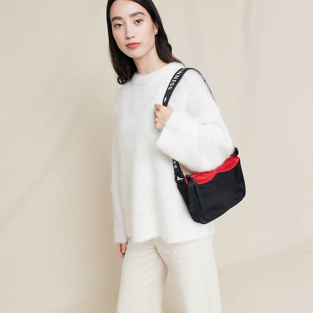Woman holding a black and red bag against a beige background