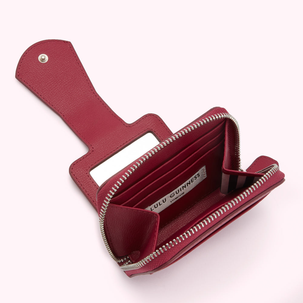 Crimson red Lulu Guinness compact mirror wallet open, showcasing its interior and small mirror.
