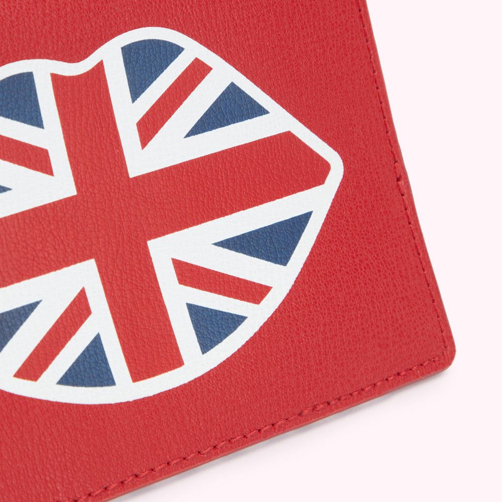 A close up image of a red leather passport cover with a lip shaped union jack print on the front.