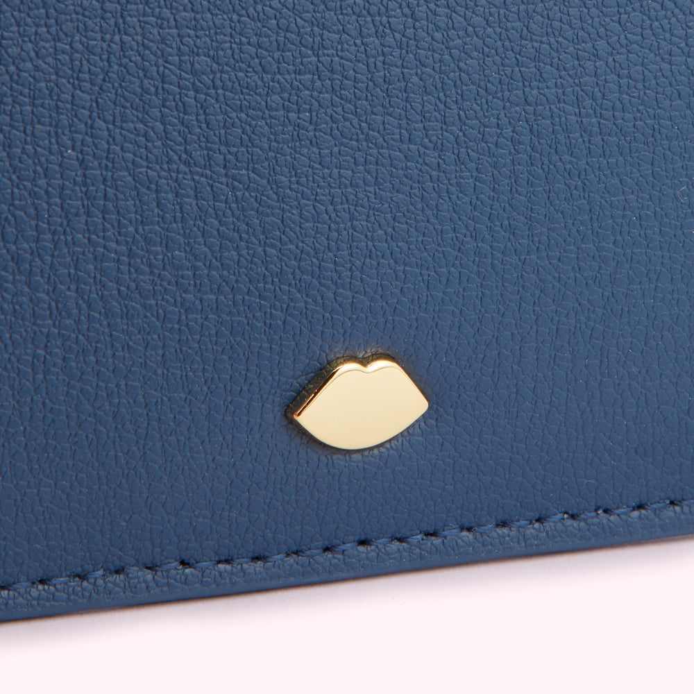 Close-up of a dark blue leather wallet with a gold lip-shaped detail.
