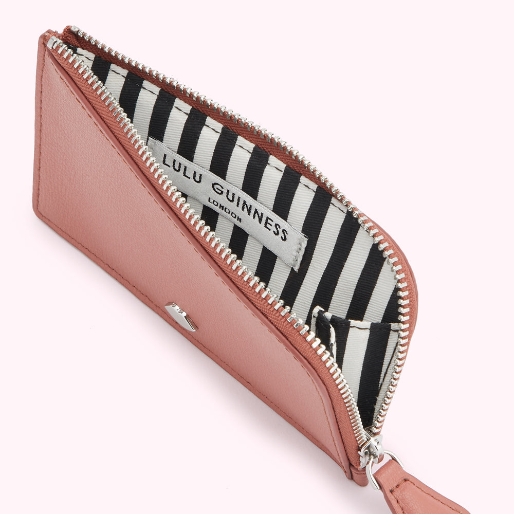 A blush pink Lulu Guinness zip-around cardholder with a black and white striped interior.
