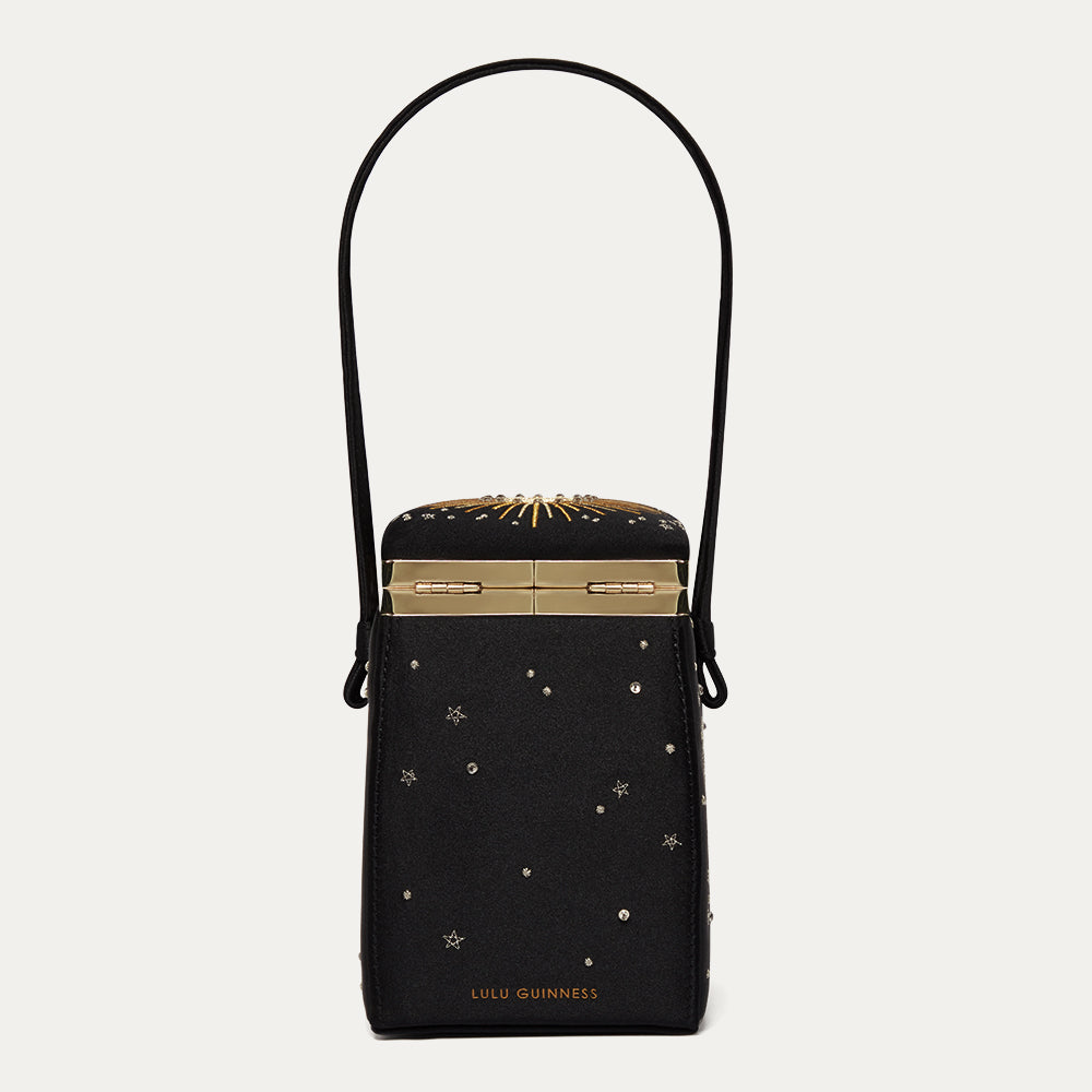 Black satin handbag with gold accents and star patterns on a light gray background