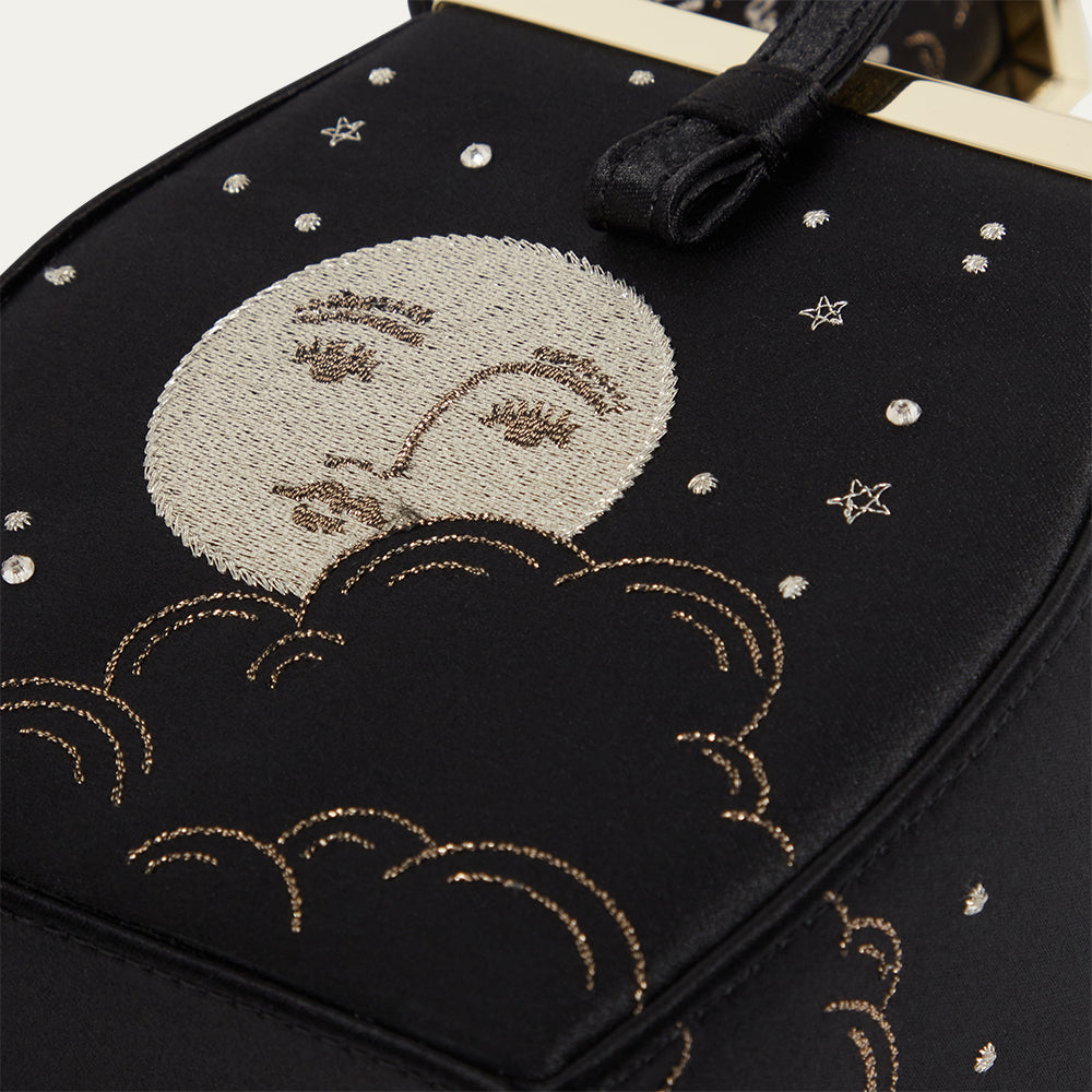 Black satin bag with embroidered moon, clouds, and stars design.