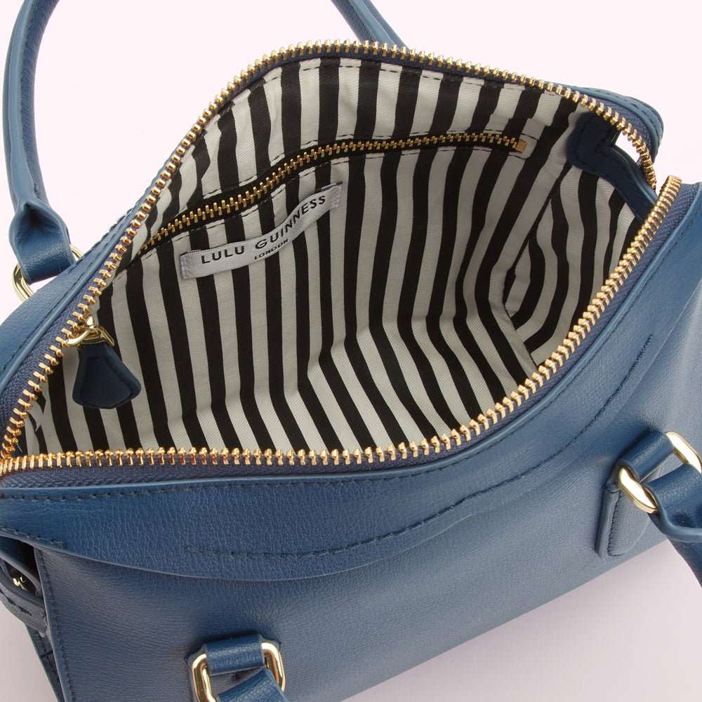 Inside of a blue Lulu Guinness handbag with a black and white striped lining.