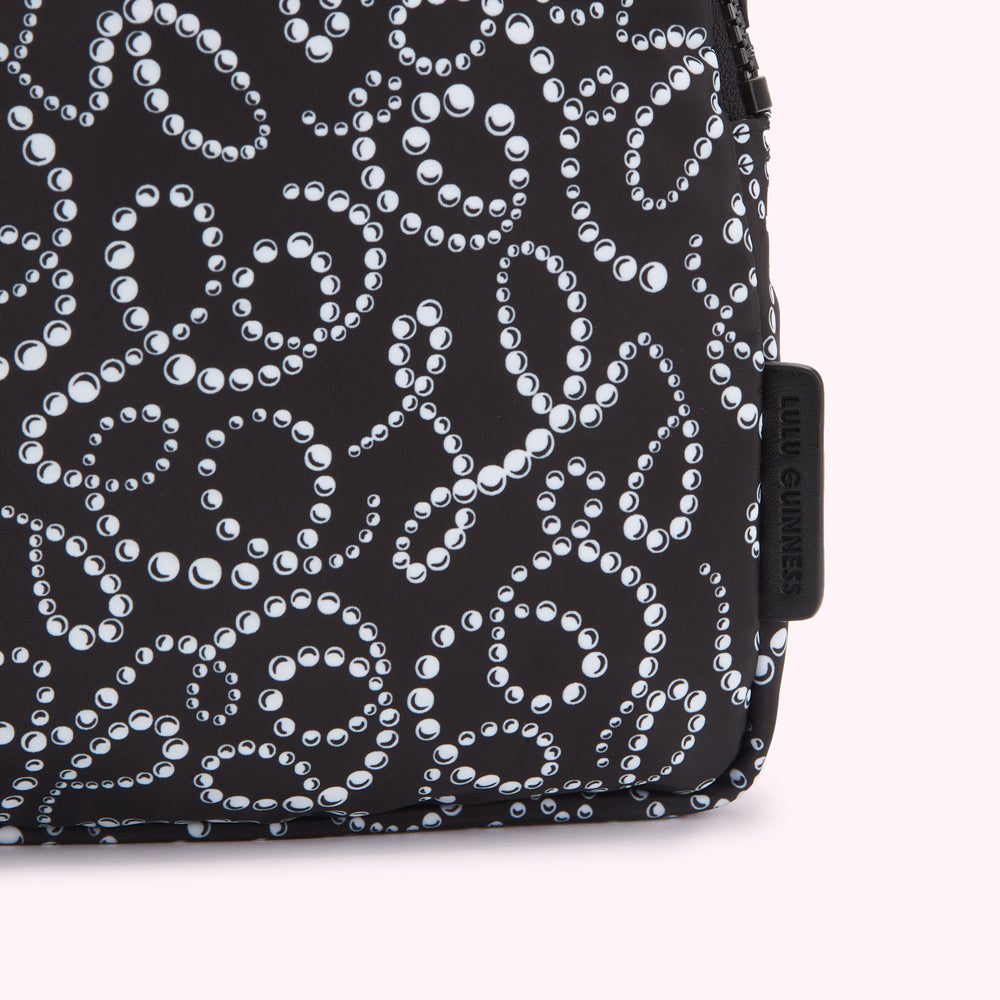 Close-up of a black Lulu Guinness cosmetic bag with a white pearl pattern.
