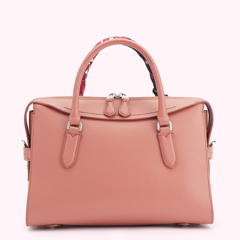 A dusty rose-coloured leather handbag with a patterned scarf accent on the handle.
