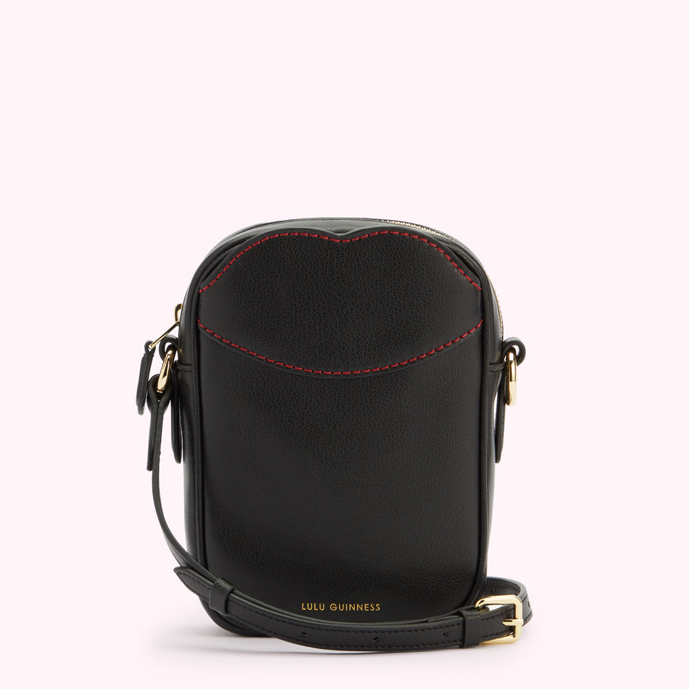 A front image of a black leather crossbody bag with gold hardware, contrasting red lip shaped stitching on the front pocket and a gold foil print 'Lulu Guinness' logo.