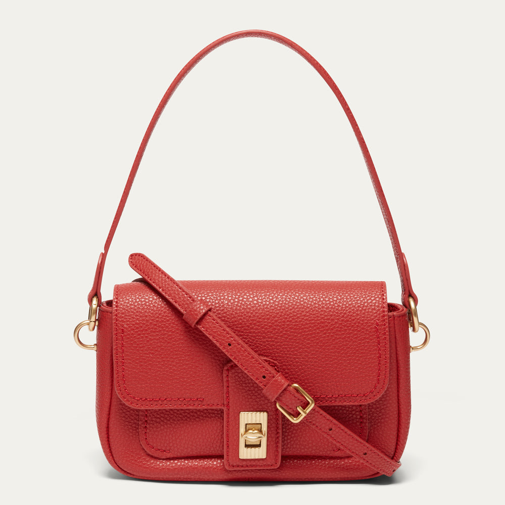 A red pebbled leather shoulder bag with a gold-tone turn-lock closure and adjustable shoulder strap, shown against a light off-white background.