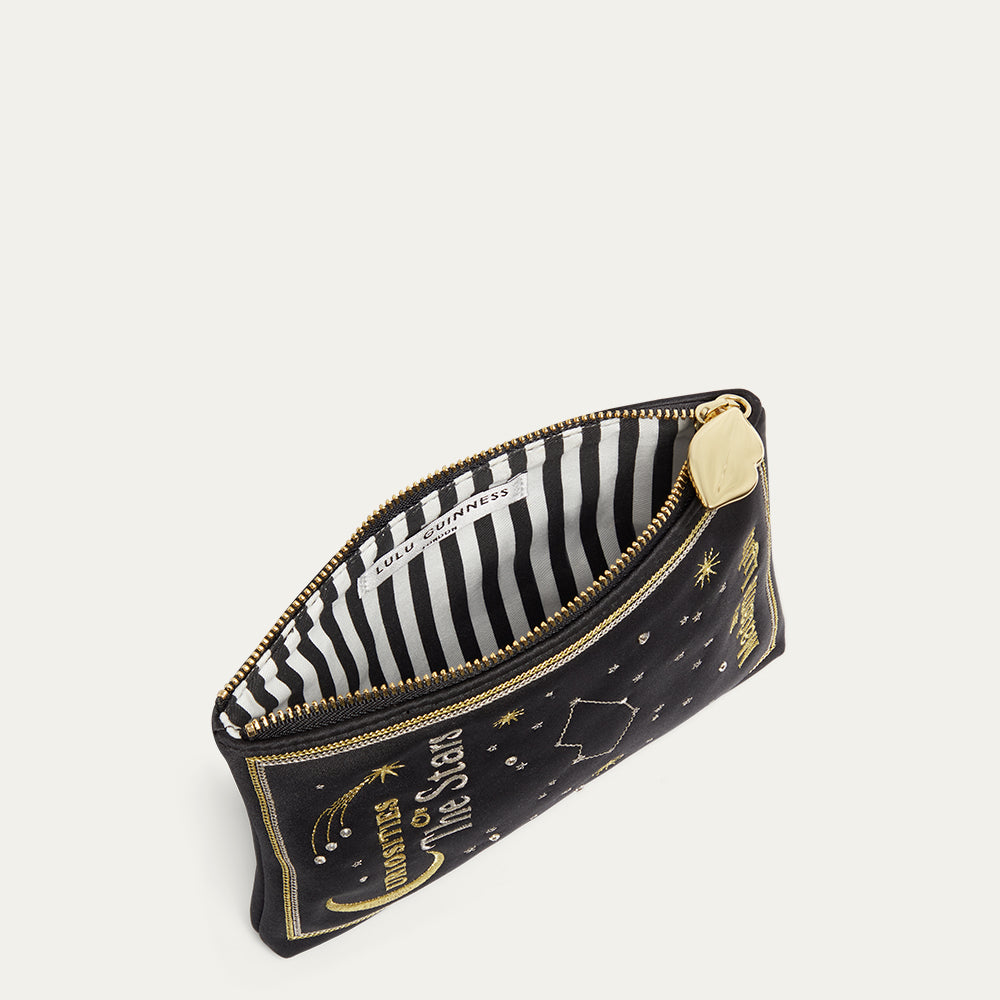 Black satin pouch with gold accents and star designs open with a black and white striped lining on a light gray background
