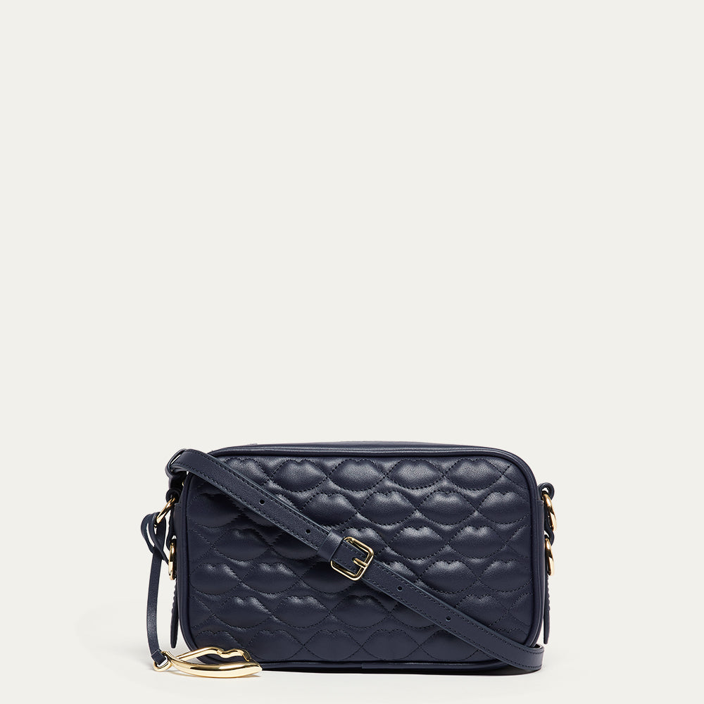 Navy blue leather quilted handbag with gold accents on a light beige background