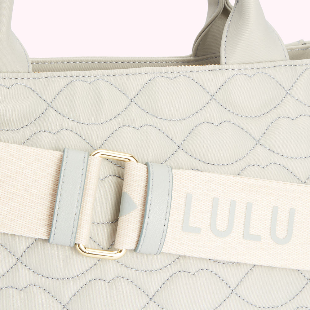 Close-up of a light grey quilted Lulu Guinness handbag with a beige and light grey strap.